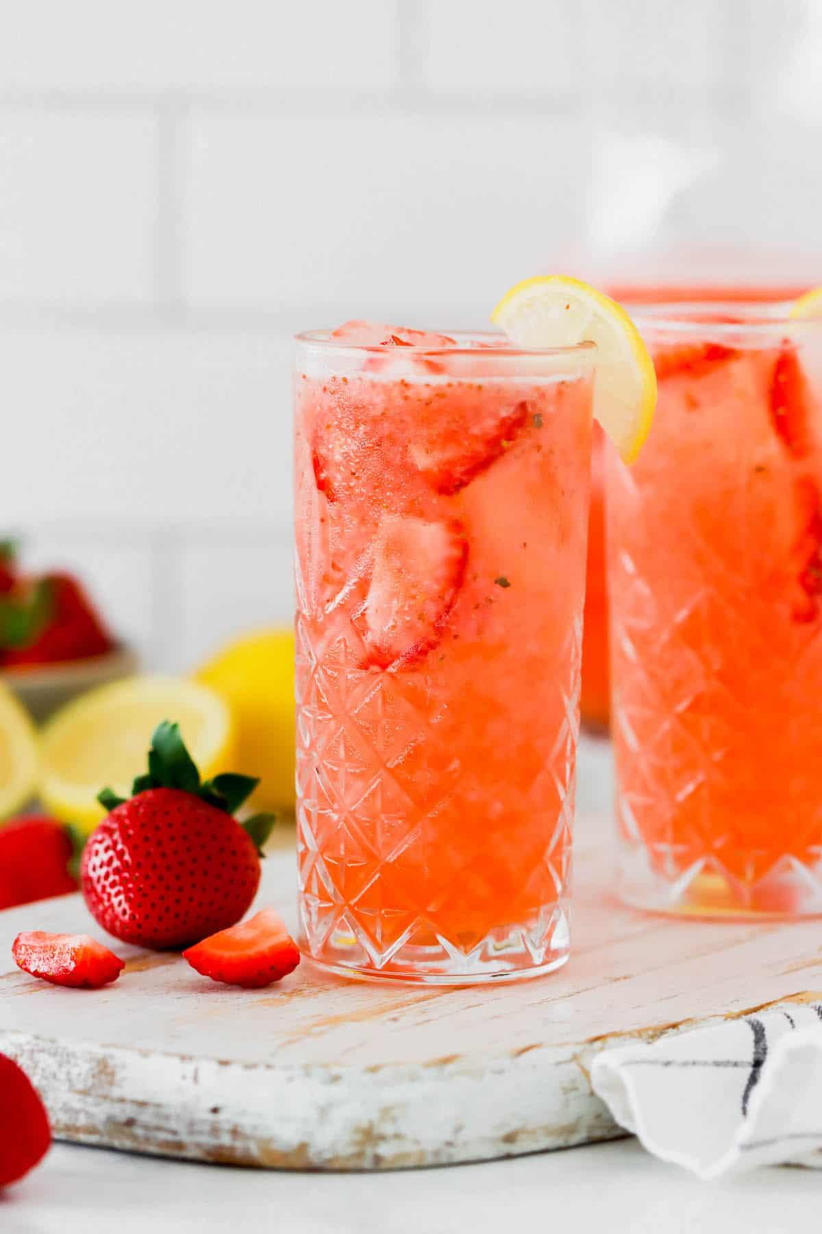 A glass of refreshing homemade strawberry lemonade with fresh strawberries and ice