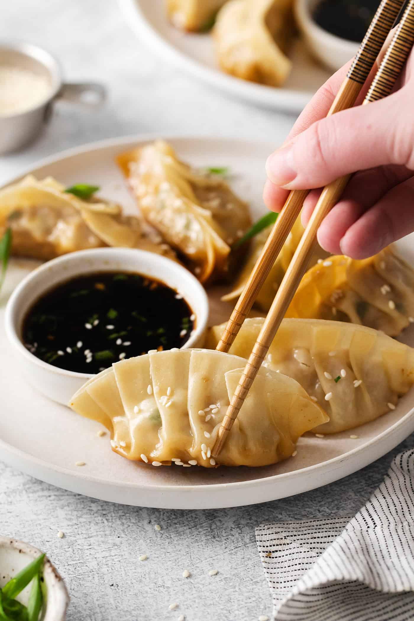 A plate of tempura-fried gyoza with chopsticks and a dipping sauce