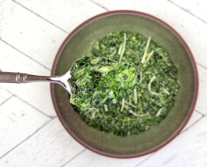 Creamed spinach close-up with a spoon scooping a portion
