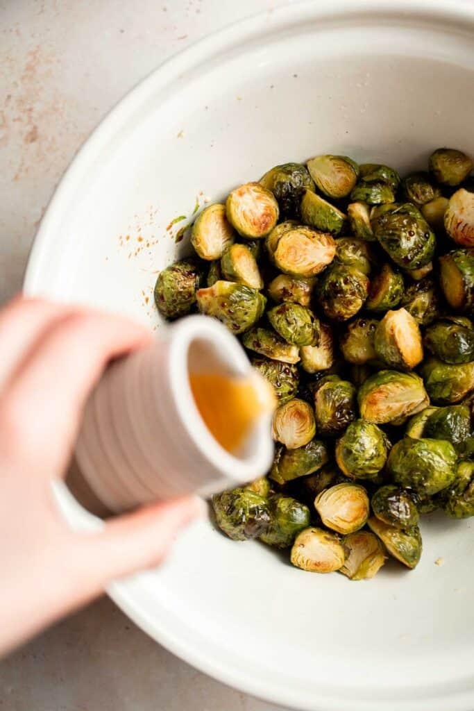 Person serving a dish of roasted Brussels sprouts