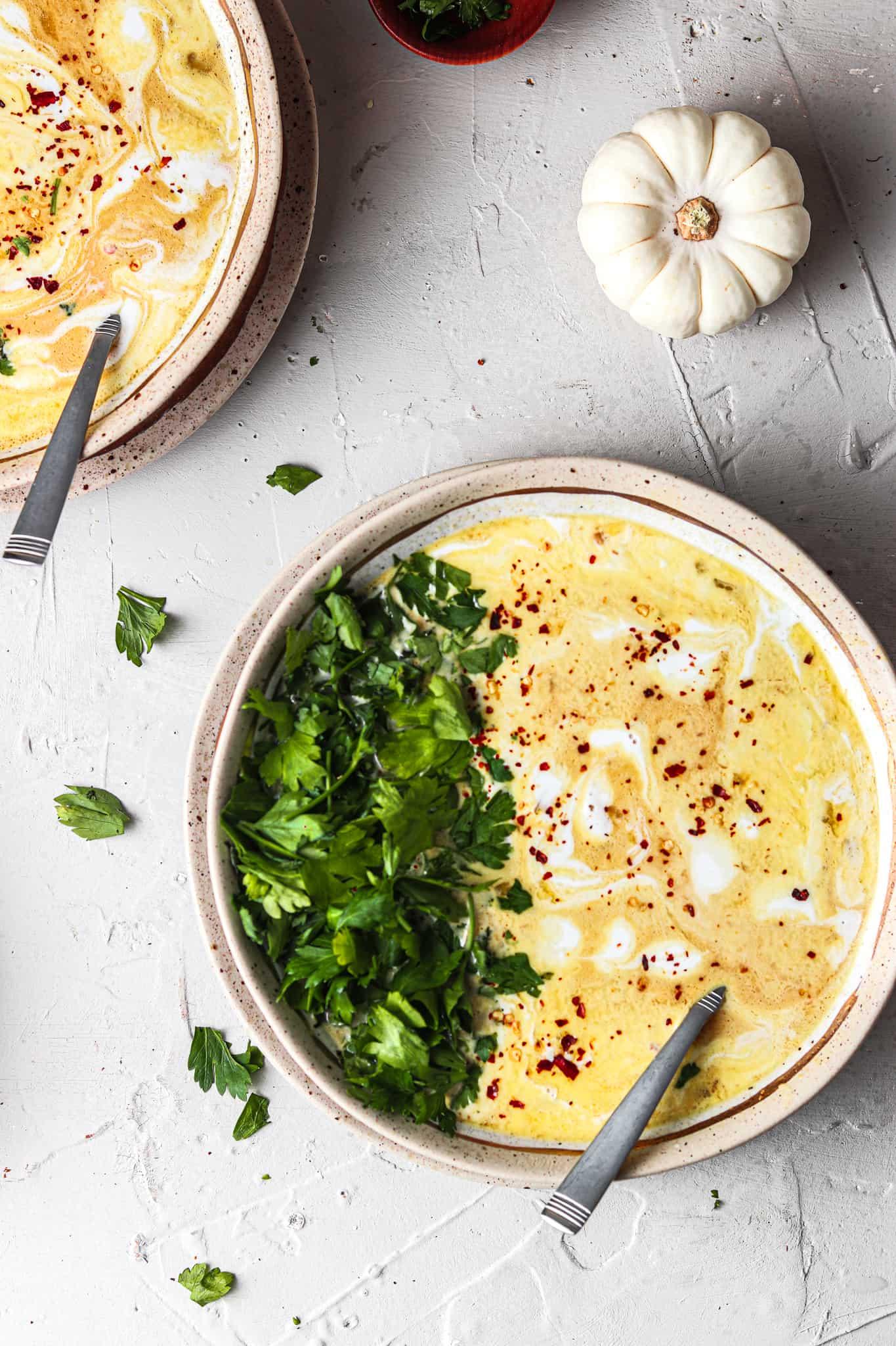 Close-up shot of a bowl of creamy pumpkin soup with grilled chicken on top