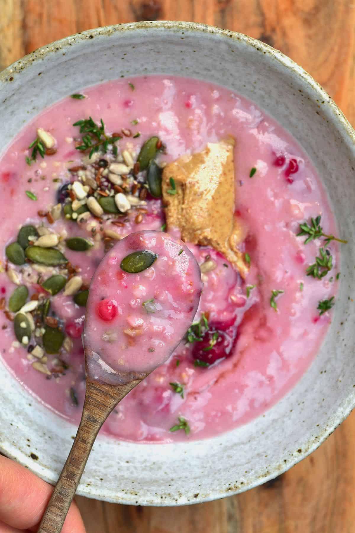 A bowl of mixed fresh berries with a spoon next to a container of rolled oats