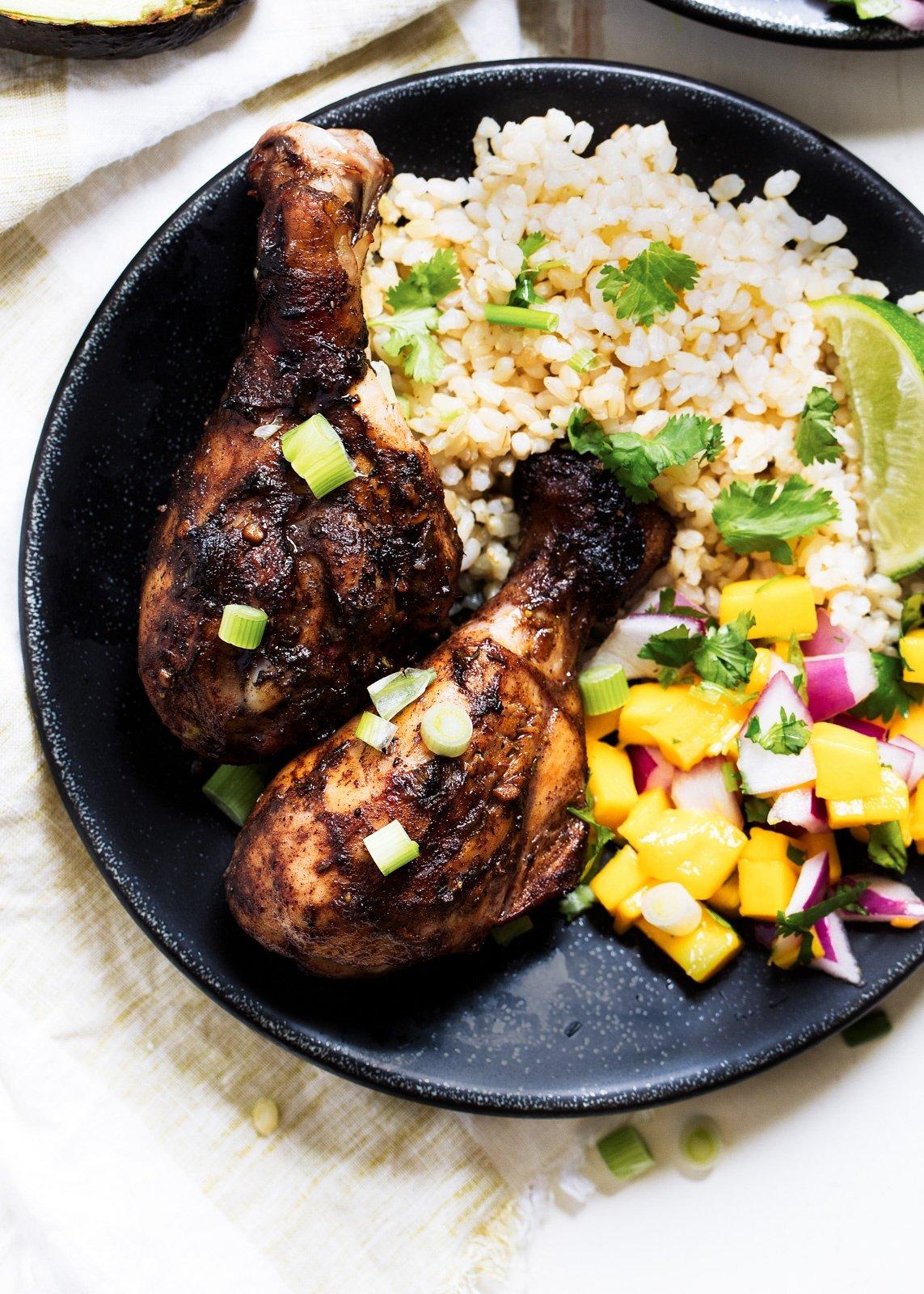 Grilled jerk chicken on a platter with sides