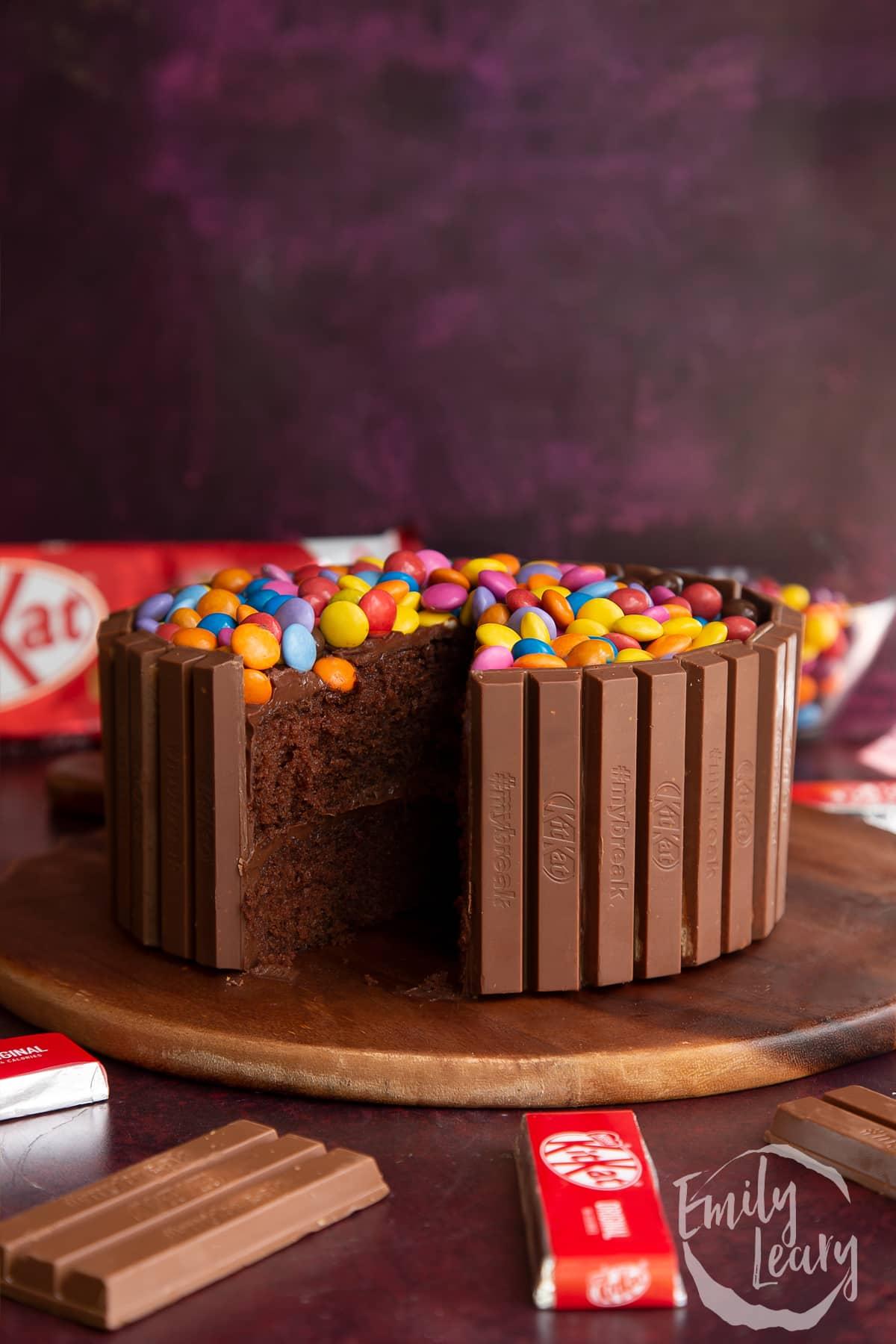 Close-up shot of a slice of Kit Kat cake being lifted, showing the cake layers and ganache