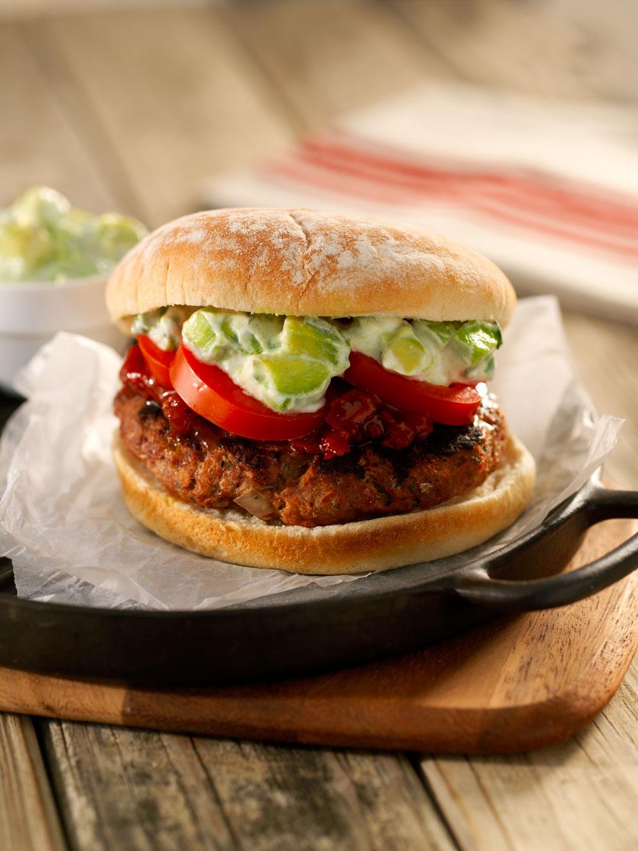 overhead shot of a beautifully assembled grilled lamb burger with avocado crema