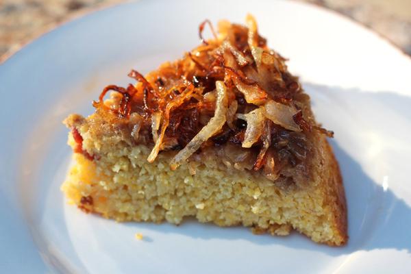 A close-up shot of a slice of cornbread with caramelized onions, showing its texture and color.