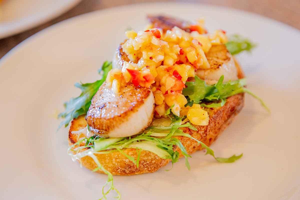 Close-up of a perfectly seared spiced lobster tail served alongside golden-brown anniversary toast