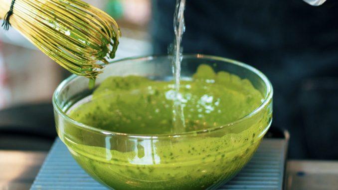 close-up shot of matcha powder being whisked into warm water