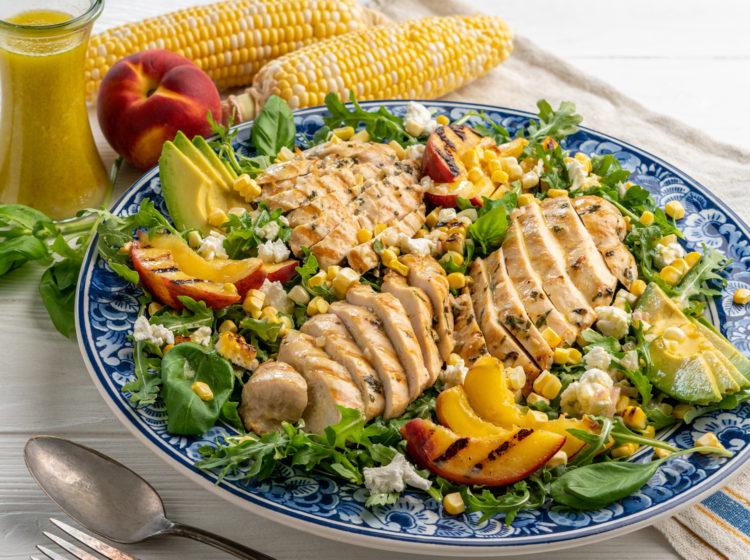 A full shot of the Grilled Corn and Peach Salad served on a platter, garnished with fresh basil.