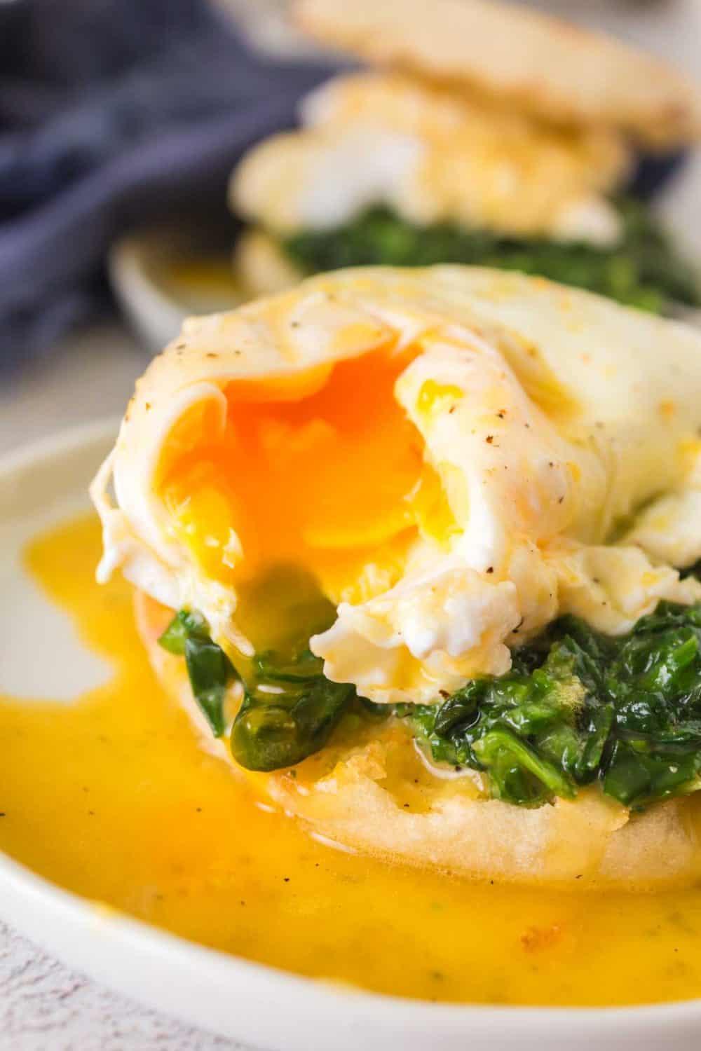 Close-up shot of perfectly cooked Florentine Eggs with a side of crusty bread and a glass of water
