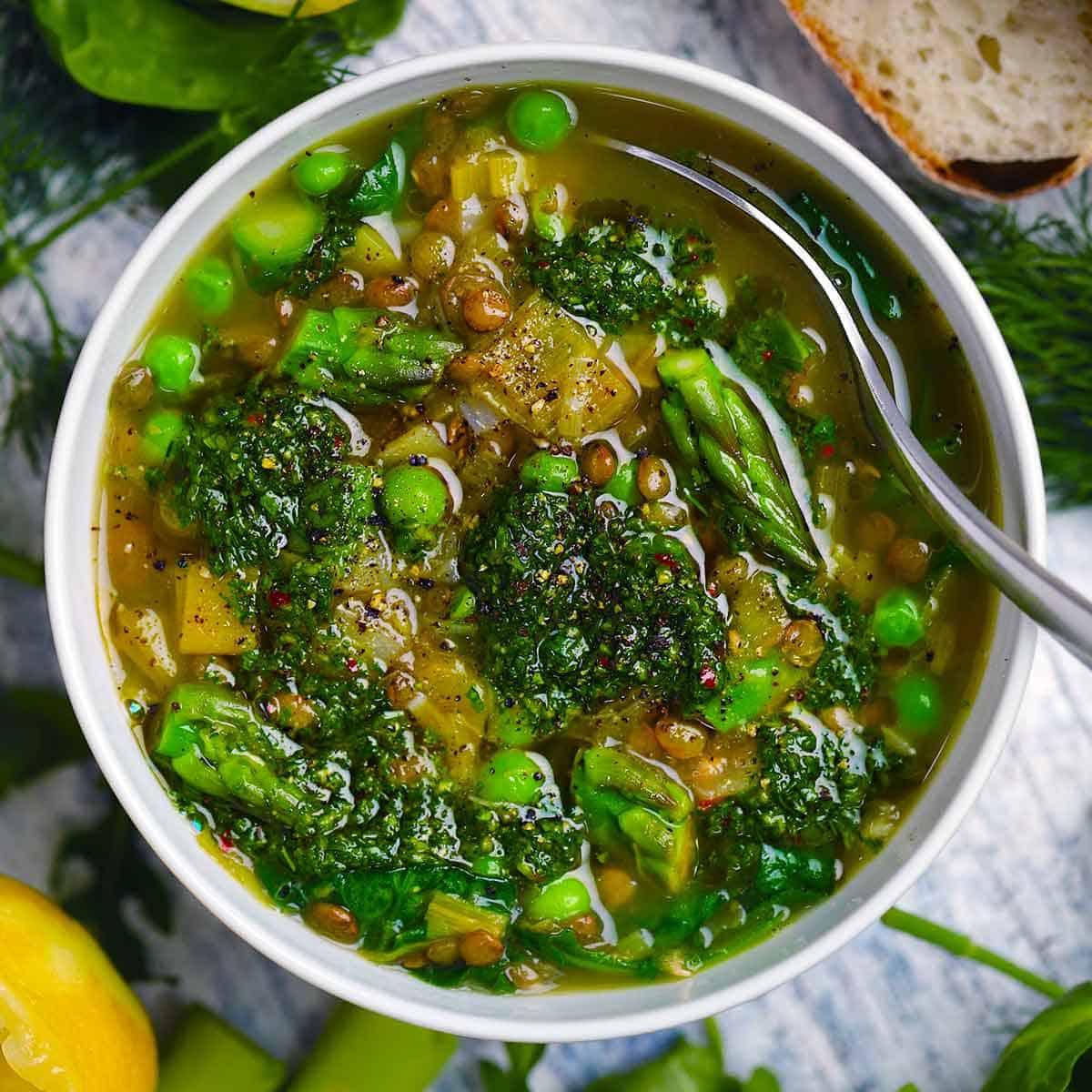 Close-up of a simmering pot of lentil vegetable stew, rich broth visible, herbs floating