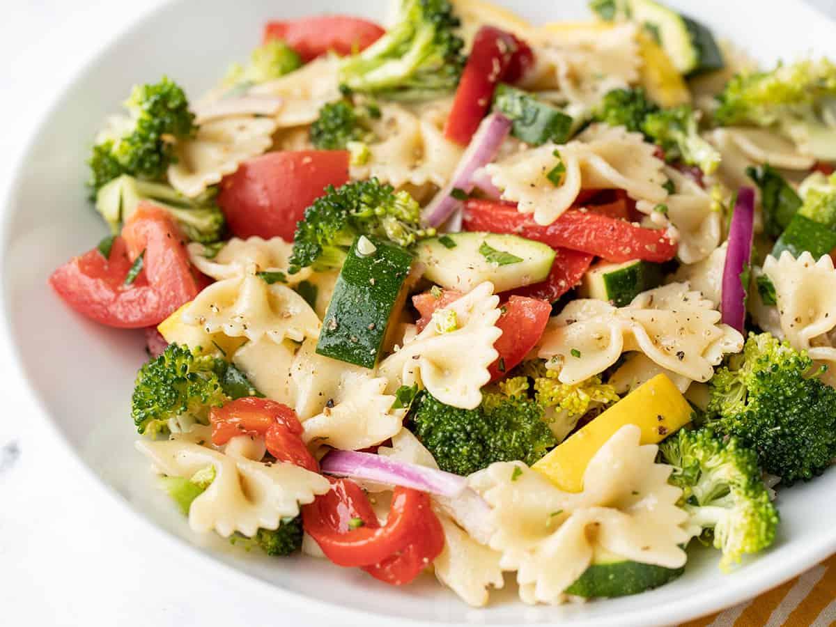 Close up of a bowl of pasta salad with bright, colorful vegetables