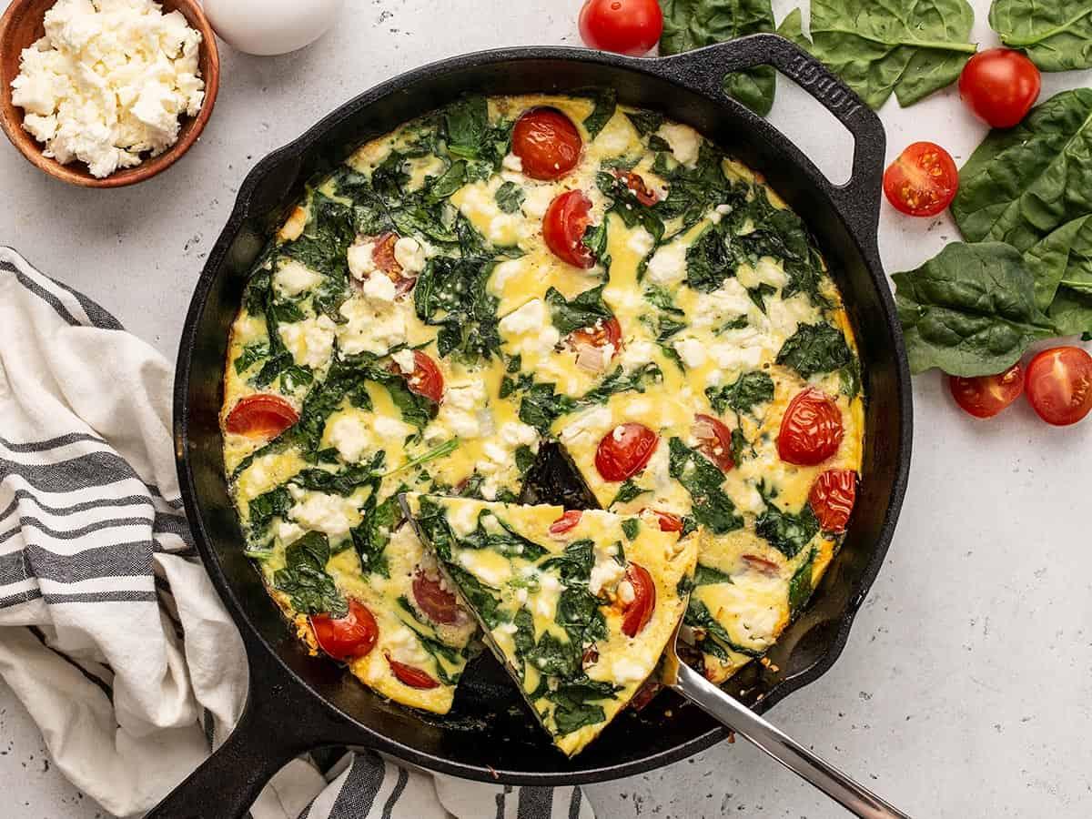 Close-up of a slice of spinach and feta frittata being lifted from the skillet