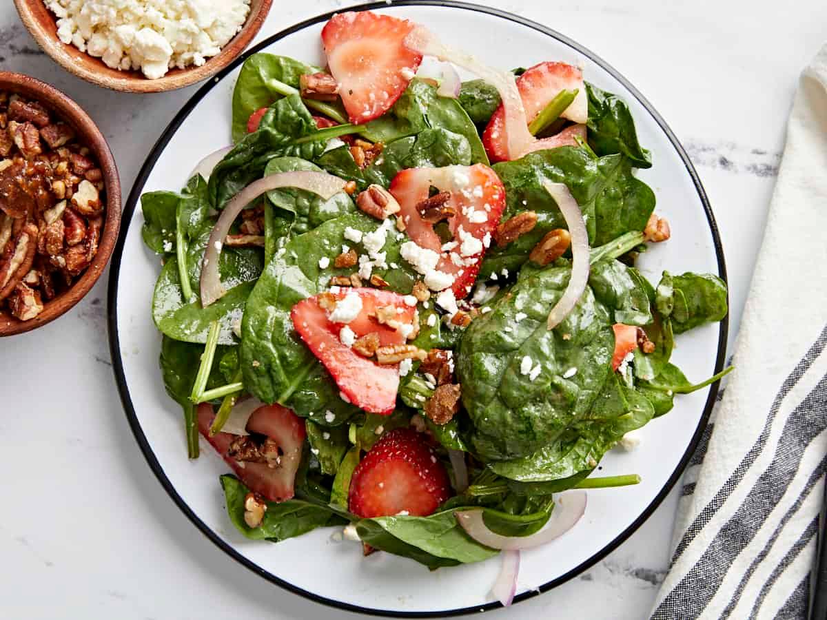 A vibrant strawberry spinach salad with candied pecans, close-up shot