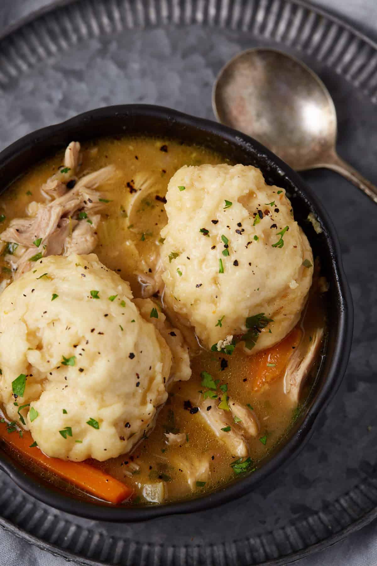 A rustic-looking pot of chicken and dumplings with a fluffy biscuit topping, shot from above