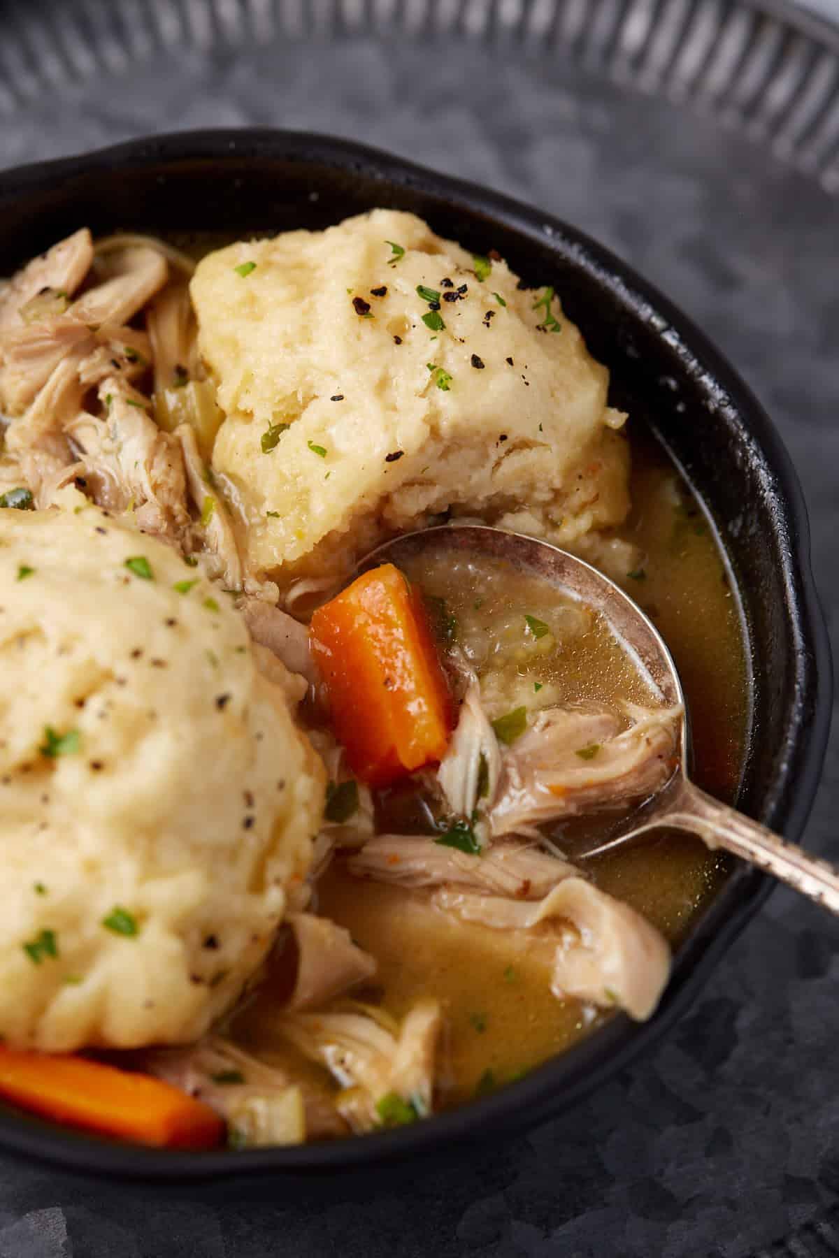 Close-up of a bowl of steaming chicken and dumplings with a golden-brown biscuit topping