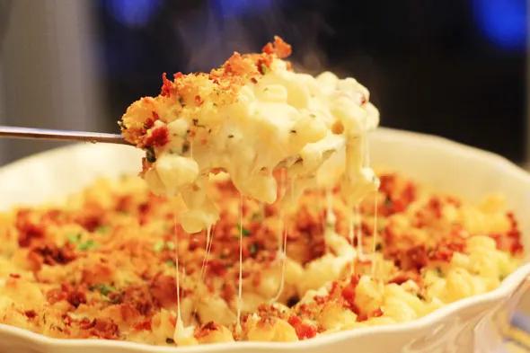 Close-up shot of creamy mac and cheese with a perfectly fried egg and crispy bacon on top