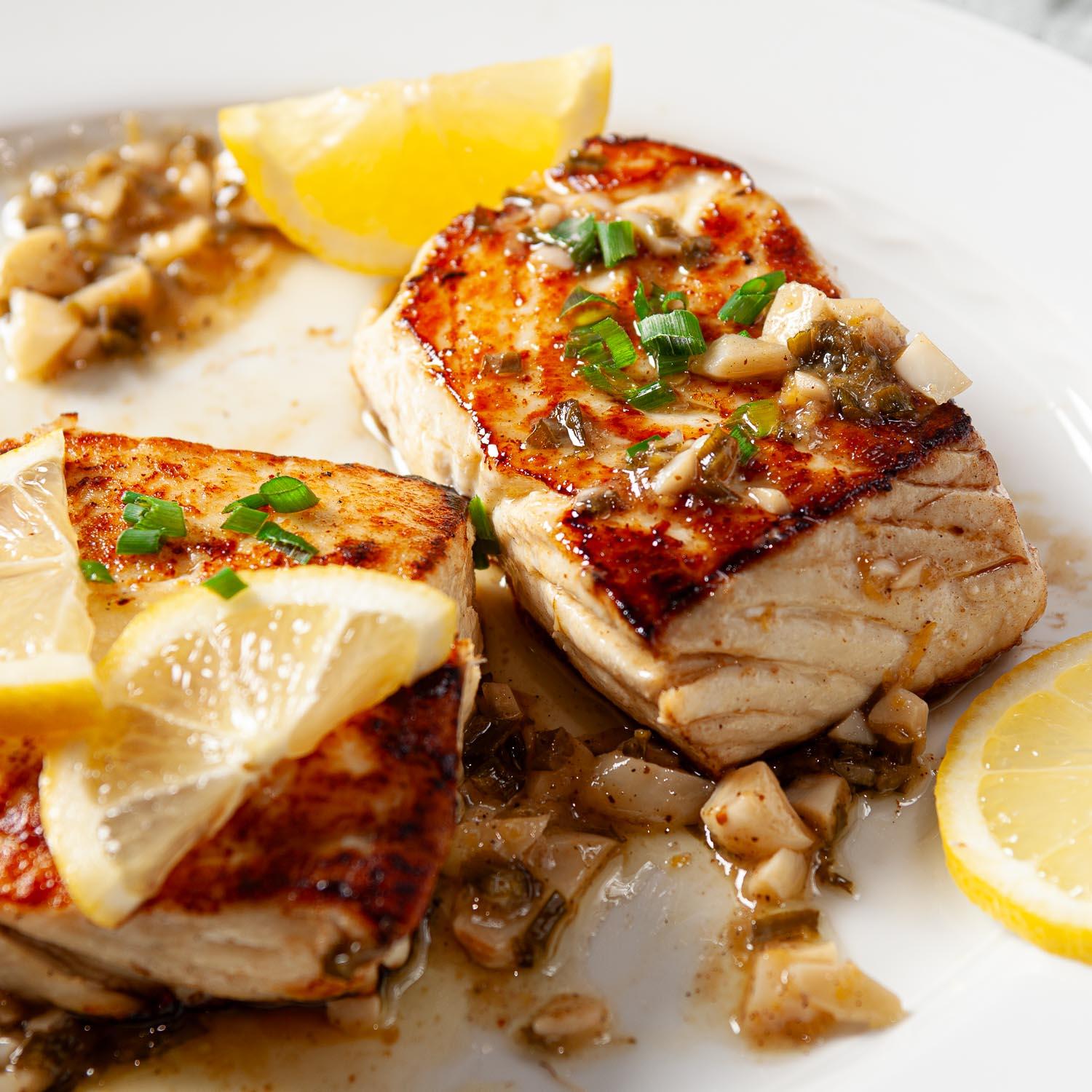 Close-up of pan-seared halibut with roasted vegetables, garnished with fresh herbs