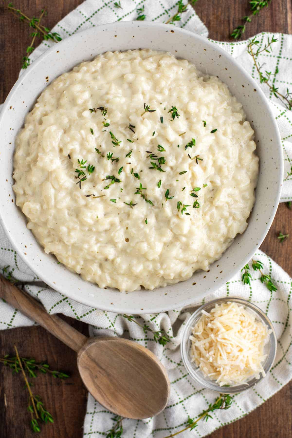 Close-up of goat cheese being crumbled over a bowl of risotto.