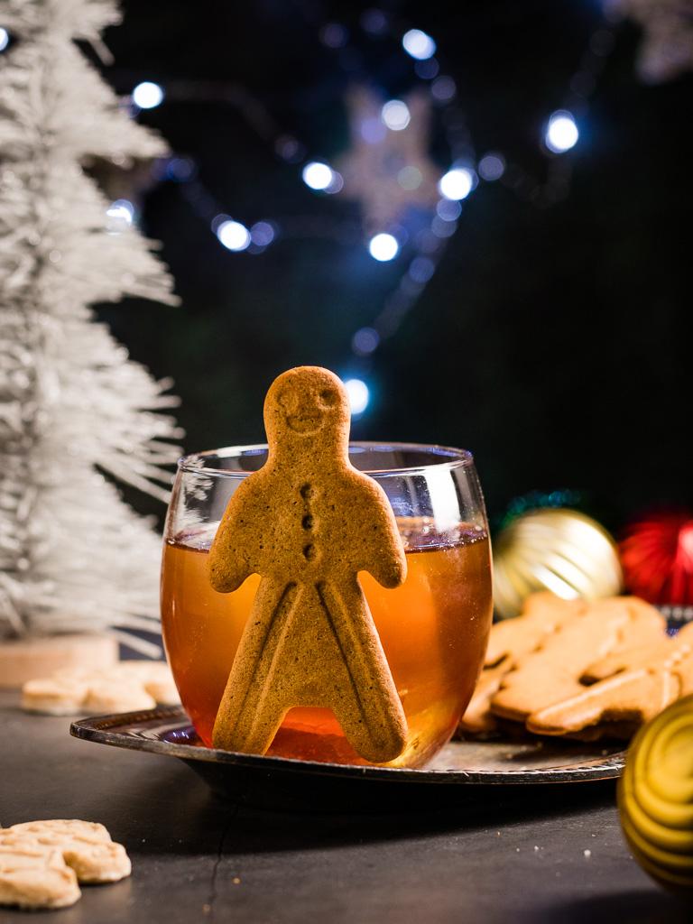 A person enjoying a Gingerbread Old Fashioned cocktail by a fireplace
