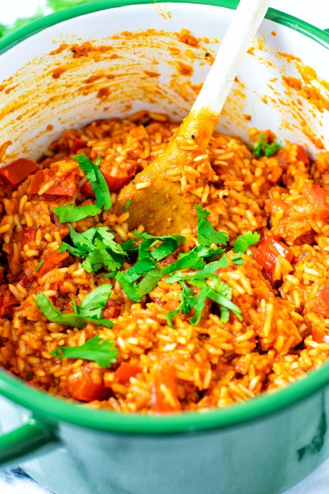 A vibrant pot of Jollof rice with oats, garnished with fresh parsley