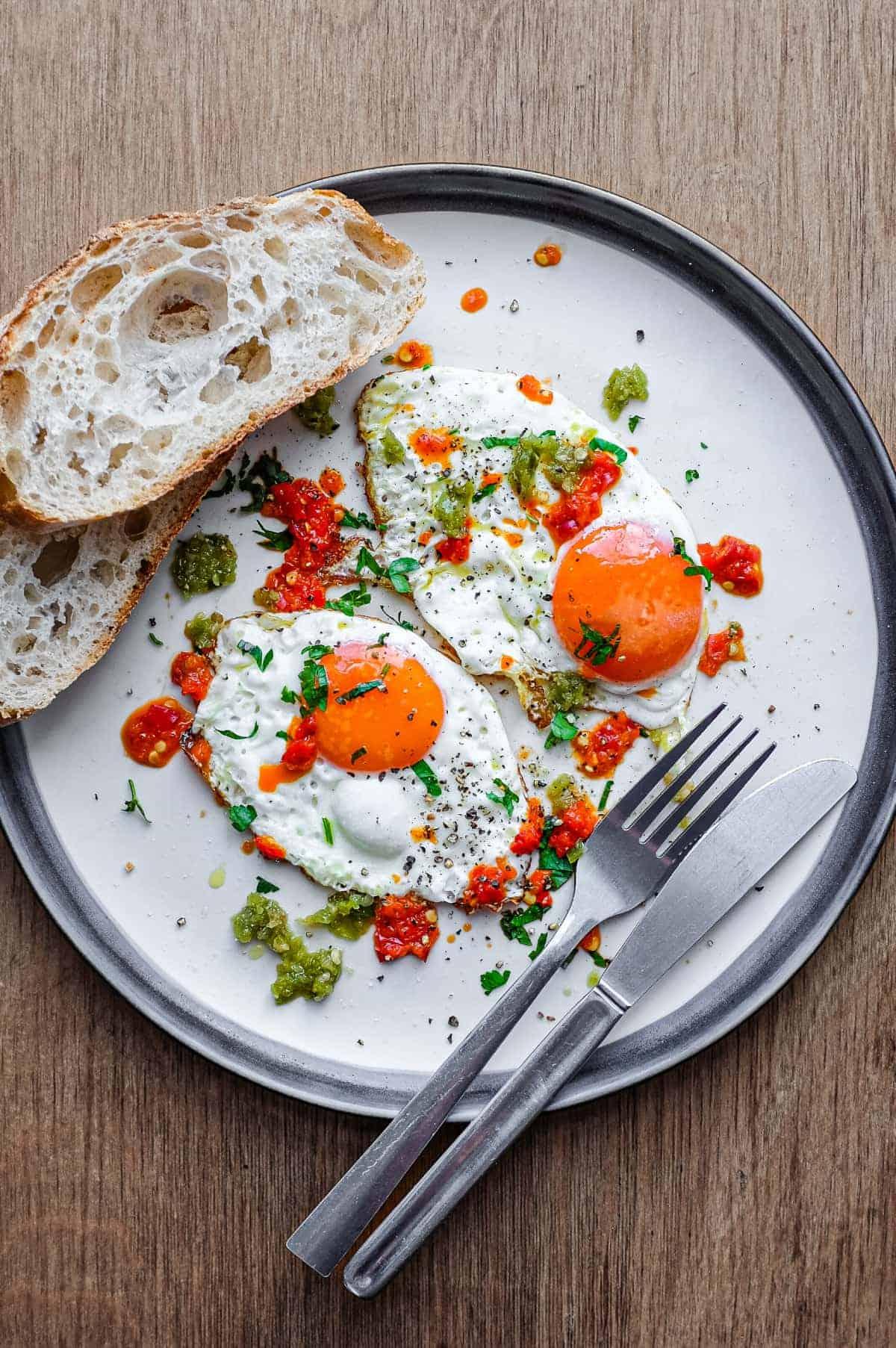 A plate of sautéed eggs with chicken broth and parsley, served with toast