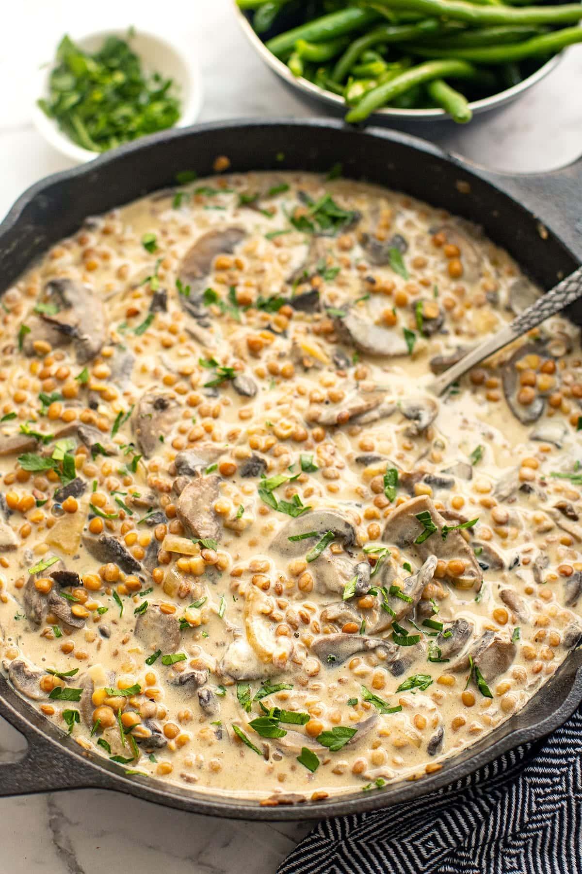close up of lentil mushroom stroganoff soup with creamy swirl and parsley garnish