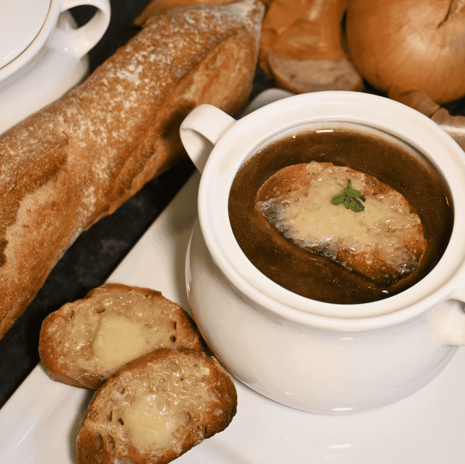 A rustic bowl of French onion soup with a golden brown Gruyere crust, garnished with fresh parsley.