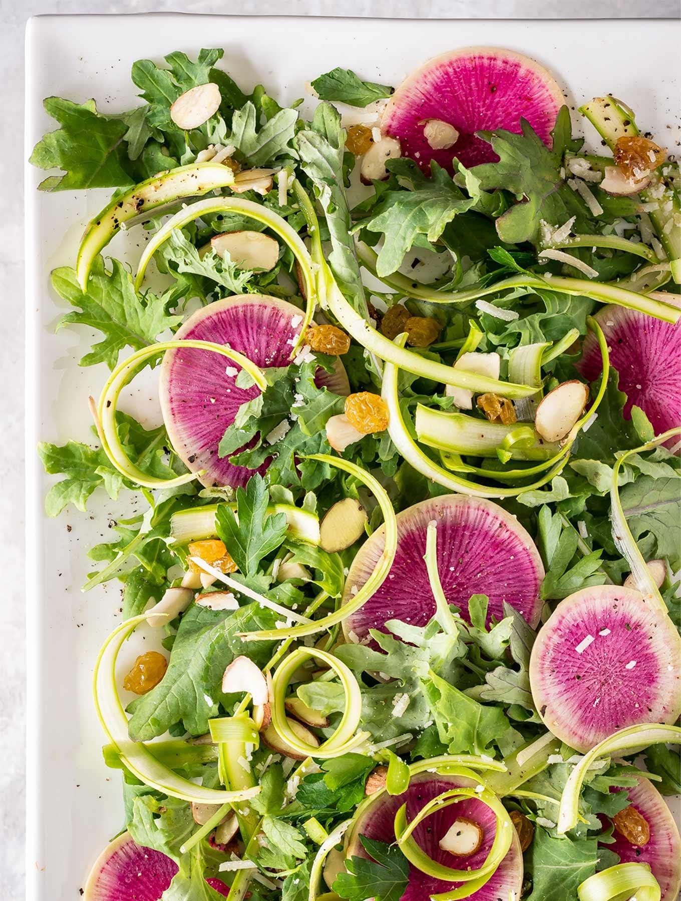 A vibrant watermelon and radish salad with a lemon-basil dressing, garnished with fresh basil leaves.