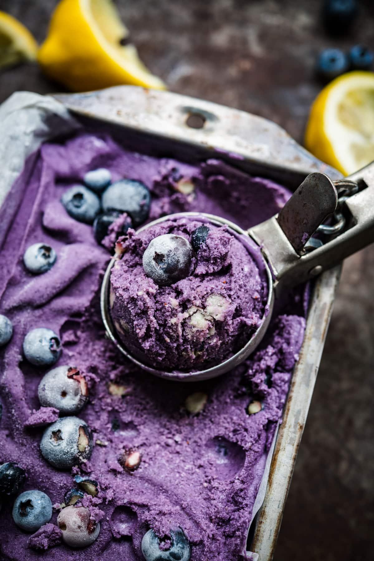 Close-up shot of a bowl of blueberry lemon ice cream with fresh blueberries and lemon slices on top