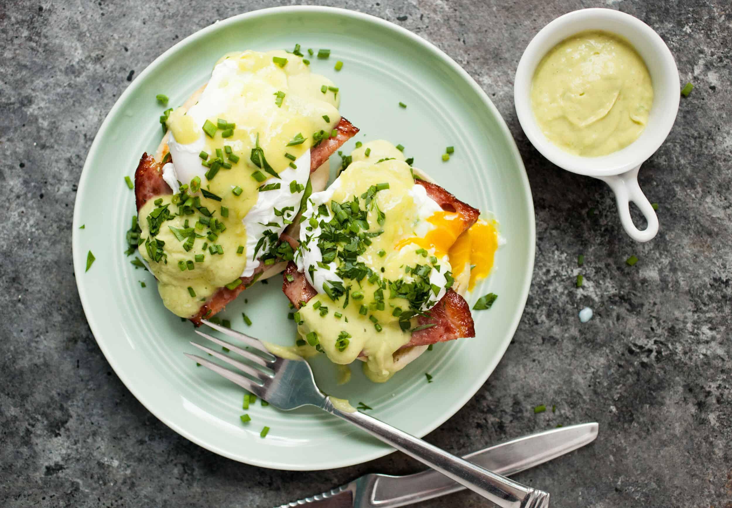 A beautifully plated Eggs Benedict with a vibrant green parsley hollandaise sauce.