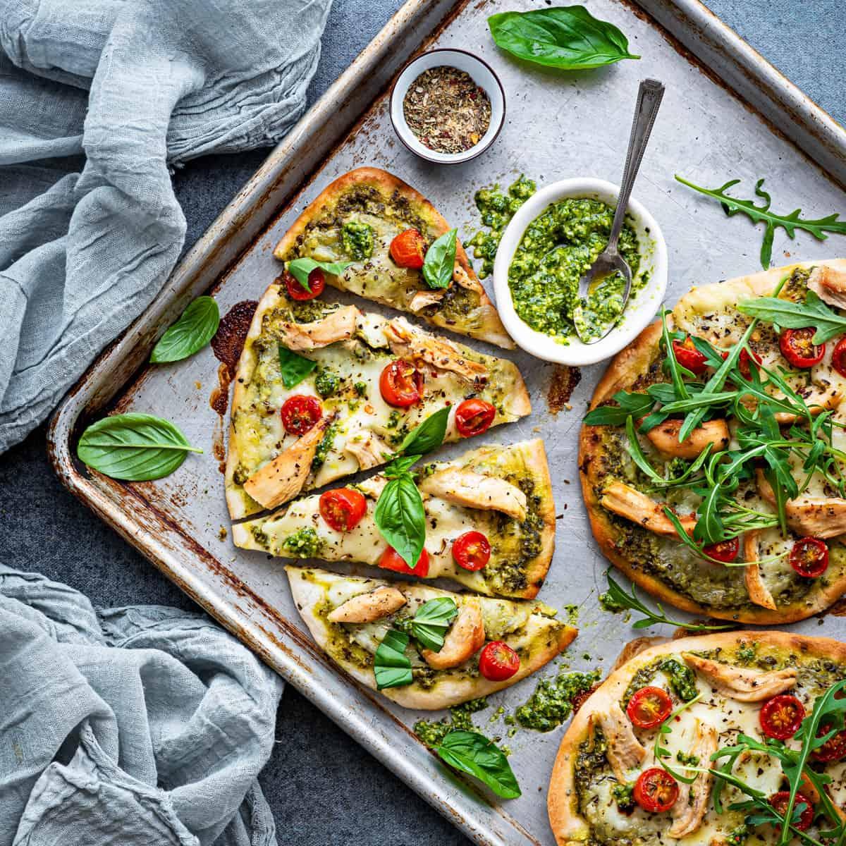 A rustic wooden table set with a delicious-looking Potato and Pea Curry Pizza with Naan Crumbles. The pizza is cut into slices, and there are naan crumbs scattered on the surface. The image is well-lit and appetizing.