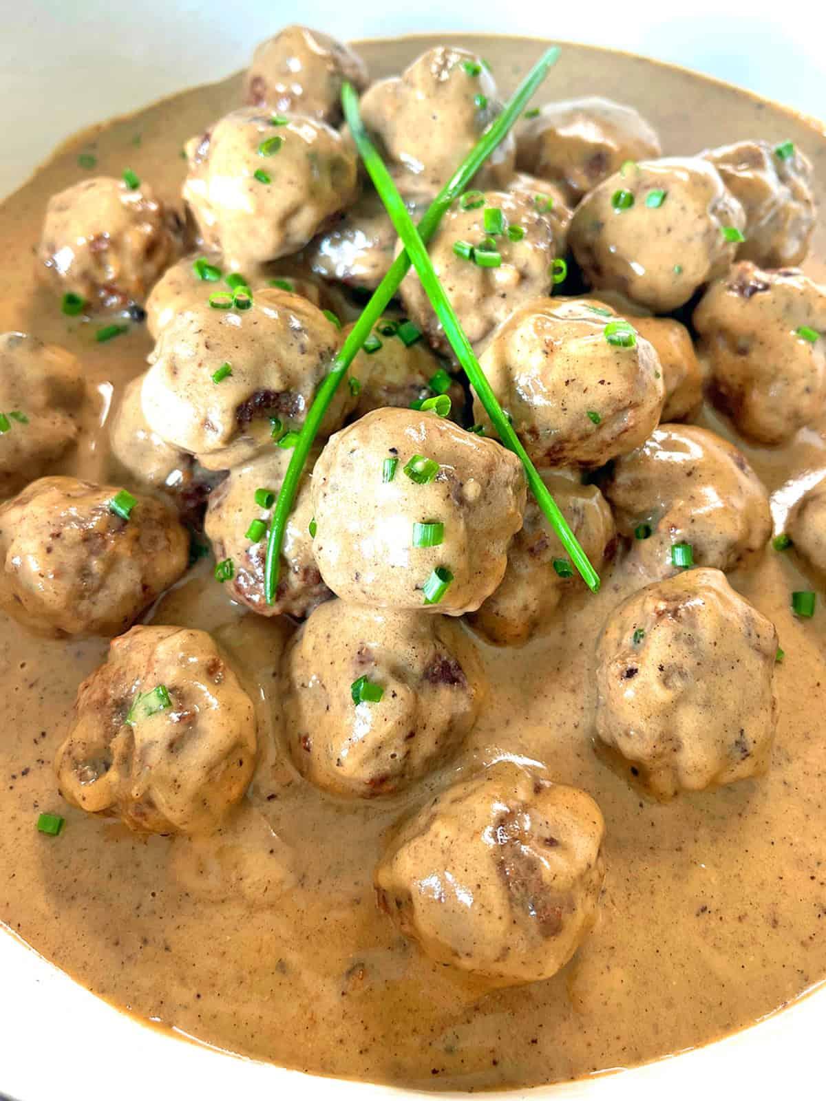 Close-up shot of delicious Swedish Kötbullar with creamy Mornay sauce, garnished with fresh parsley