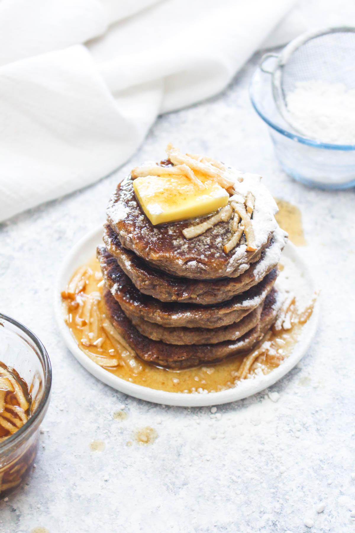 Close-up shot of fluffy pear pancakes on a plate, drizzled with maple syrup