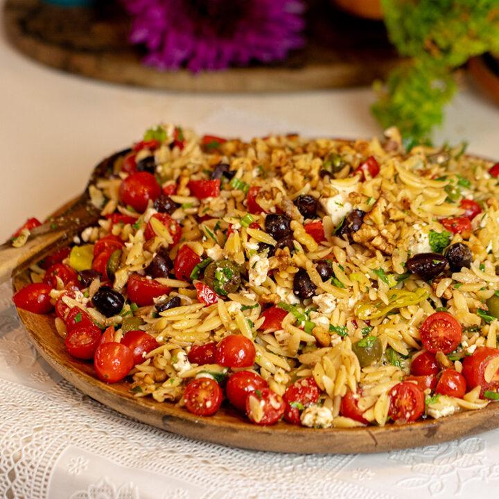 A table set with bowls of Mediterranean Orzo Pasta Soup, crusty bread, and a salad
