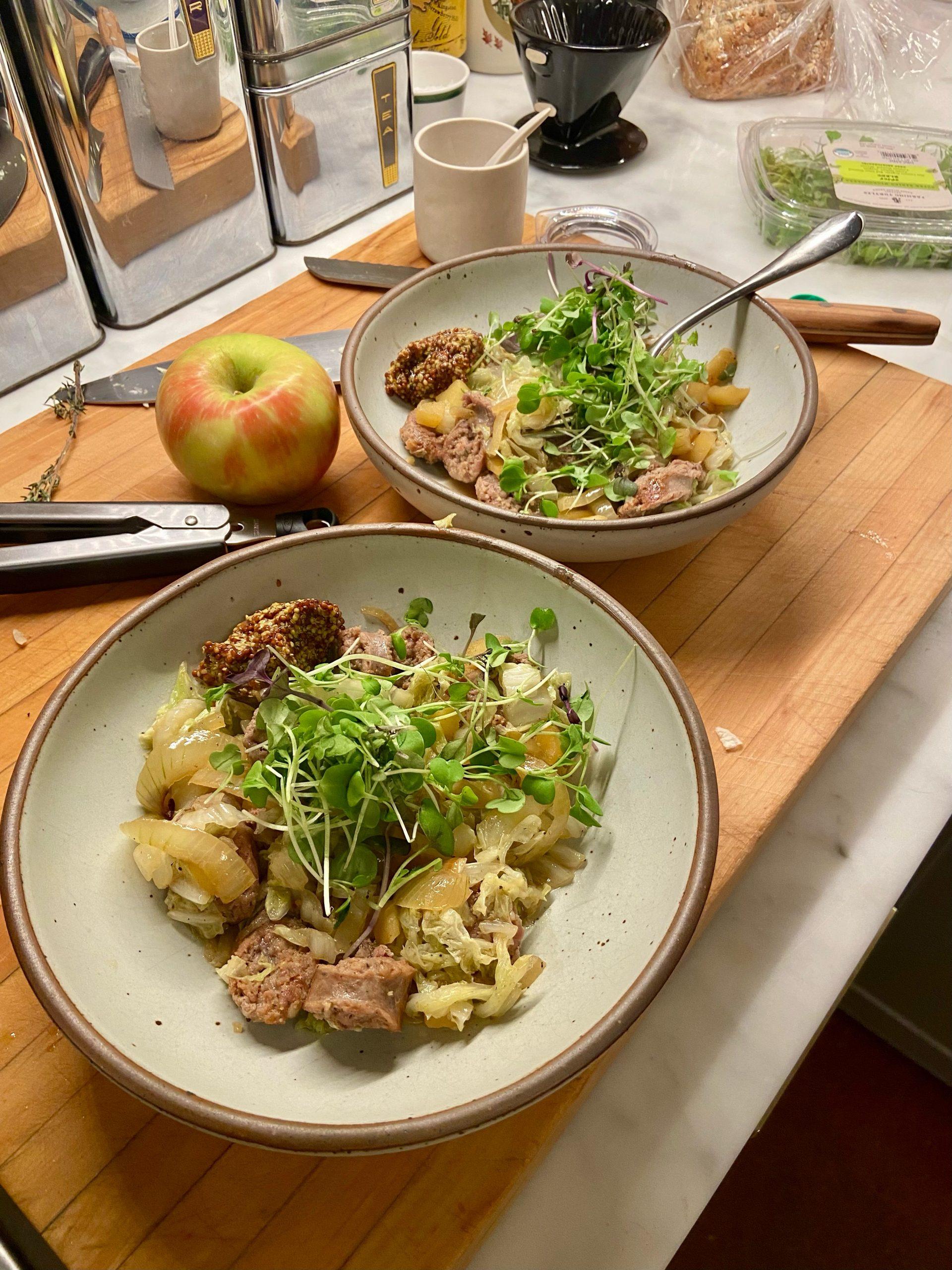 overhead shot of sausage and cabbage stew with apples in bowls