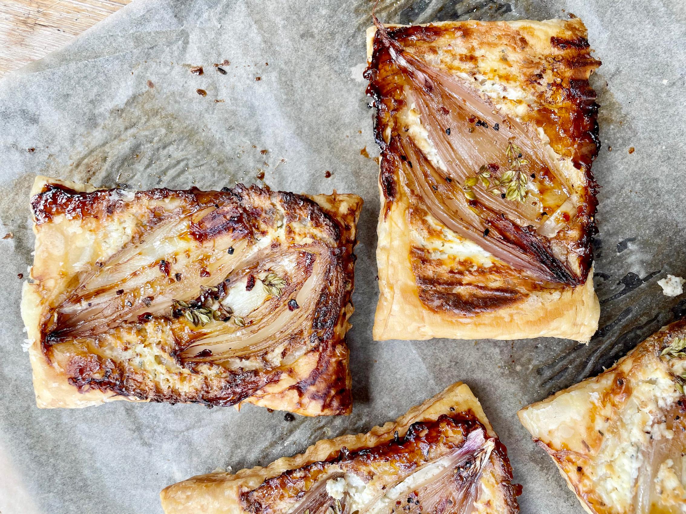 Close-up shot of a slice of paprika and caramelized onion tart, showing the layers of caramelized onions and golden puff pastry