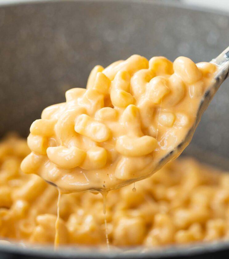 A close-up shot of creamy mac and cheese being stirred in a pot