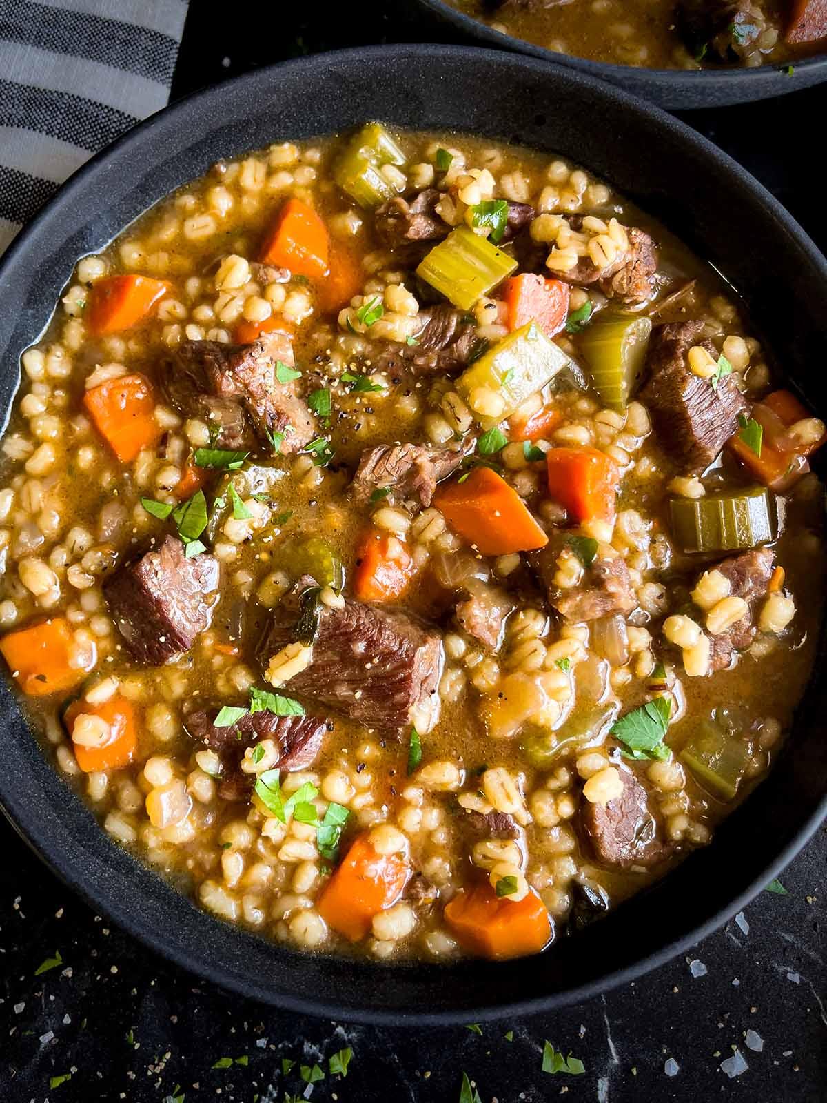 A hearty bowl of keto beef barley soup with barley substitute, garnished with fresh parsley