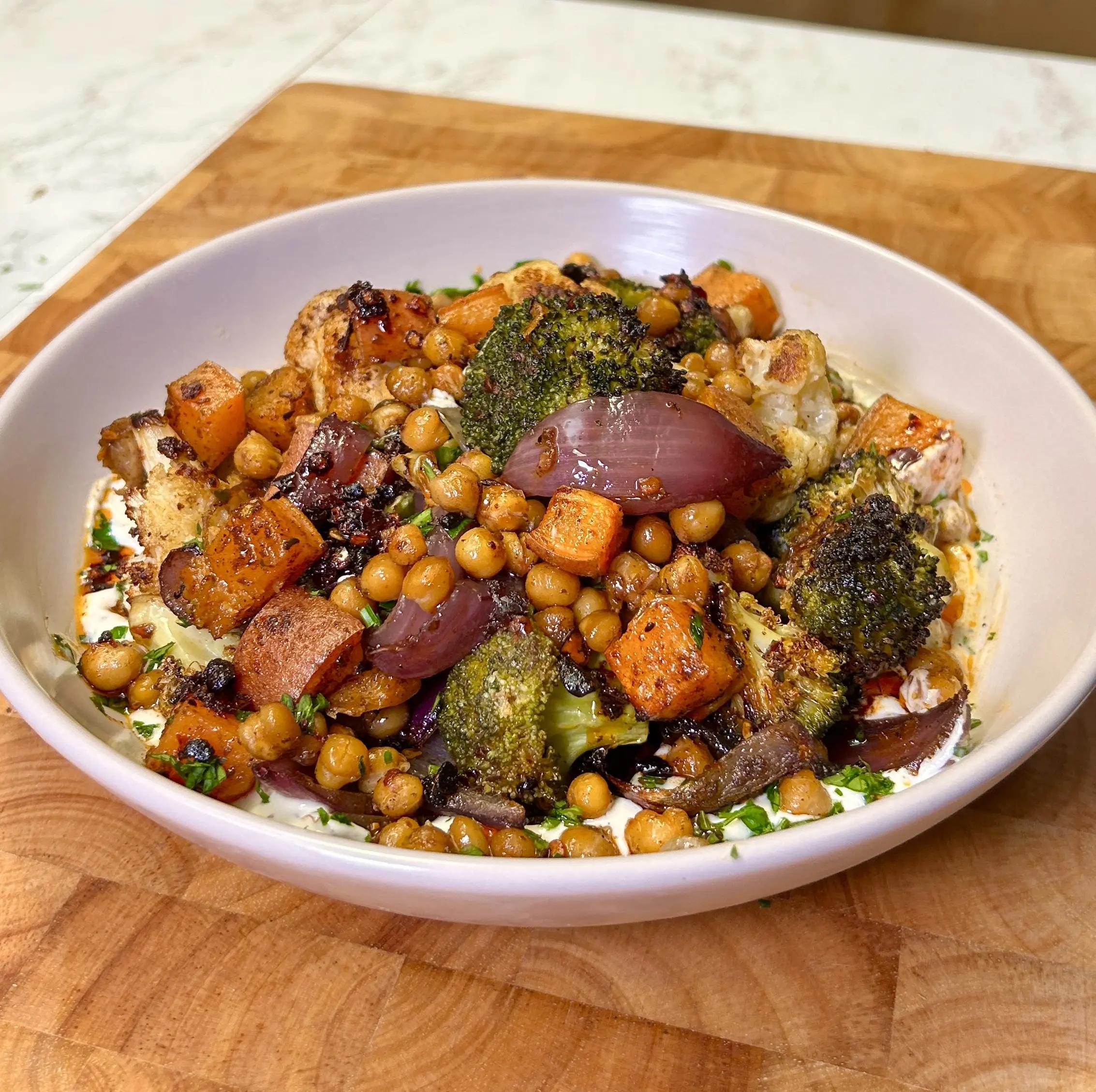 A close-up shot of warm, soft rotis served with colorful roasted vegetables and a creamy tahini dressing