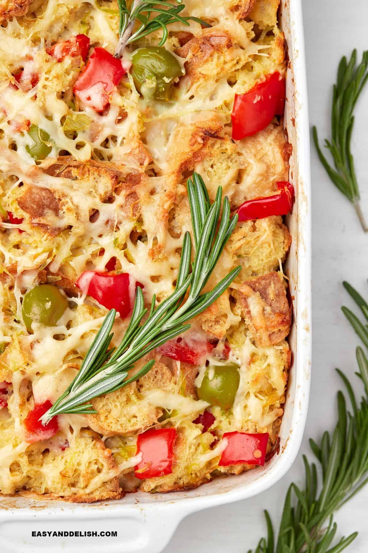 Close-up shot of a slice of savory bread pudding being lifted from the baking dish, showcasing the cheesy, custardy interior and golden-brown crust