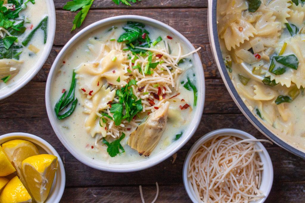 Close-up shot of creamy spinach and artichoke udon noodles in a bowl
