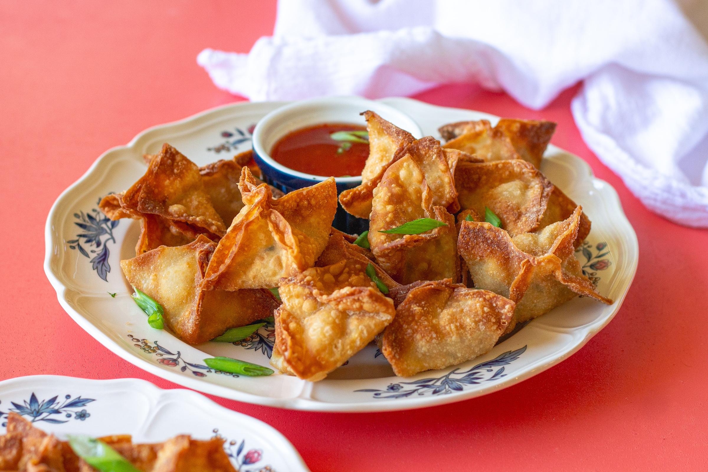 Overhead shot of a platter of Crab Rangoon Deviled Eggs garnished with green onions and wonton chips