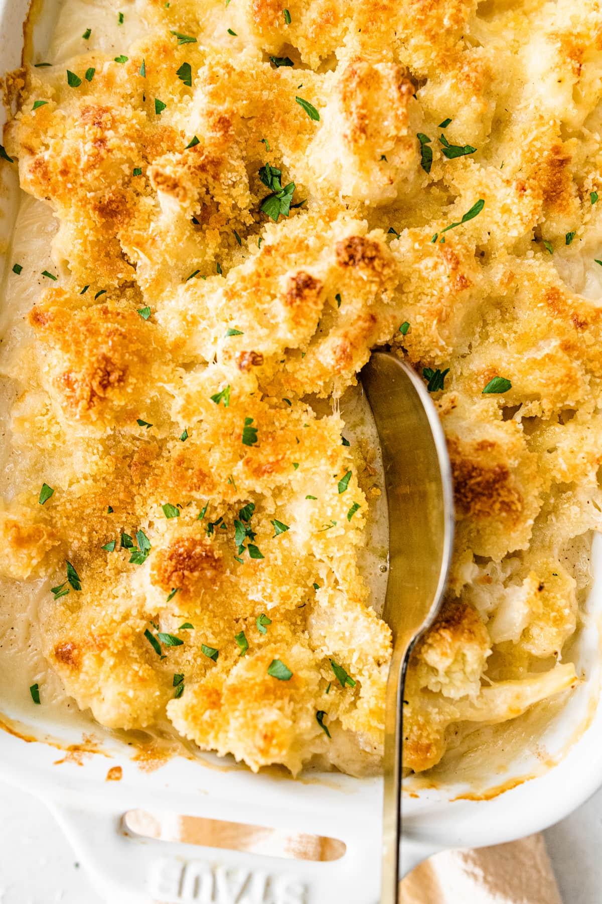 Close up shot of a creamy squash and cauliflower gratin, showing the texture of the roasted vegetables and melted cheese.