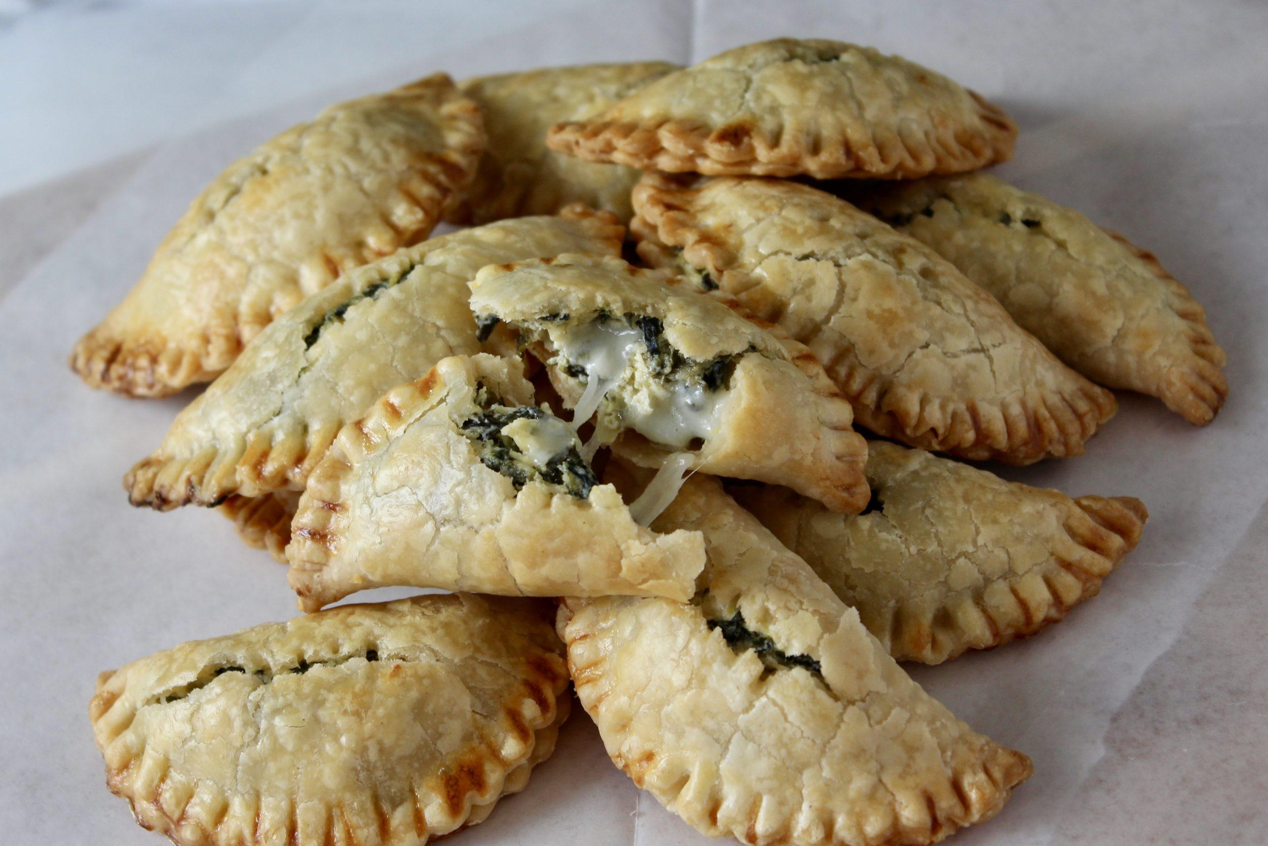 golden brown spinach and artichoke empanadas on a baking sheet