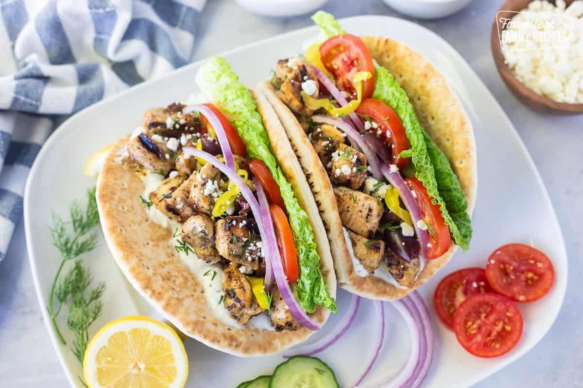 a spread of gyro toppings, including sliced tomatoes, cucumbers, red onions, and tzatziki sauce