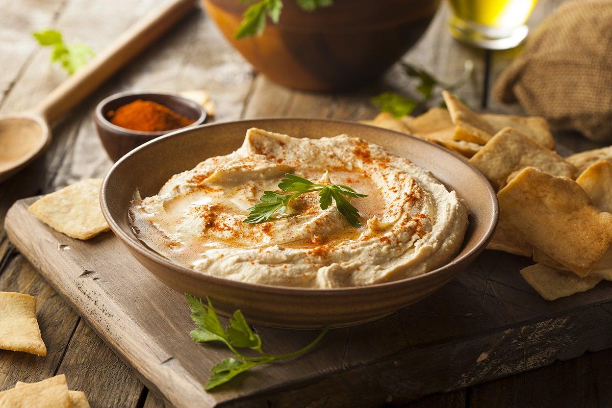 A rustic setting with a bowl of hummus and chips, suggesting relaxation and enjoyment