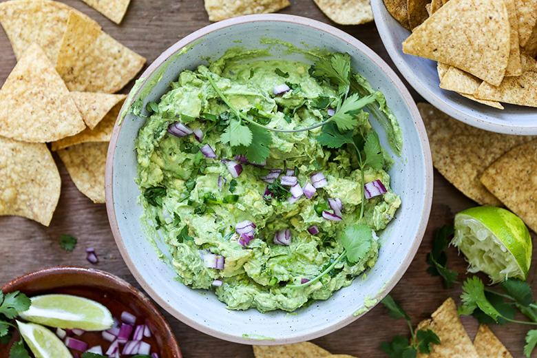 vibrant green guacamole with a dollop of yogurt, served with tortilla chips
