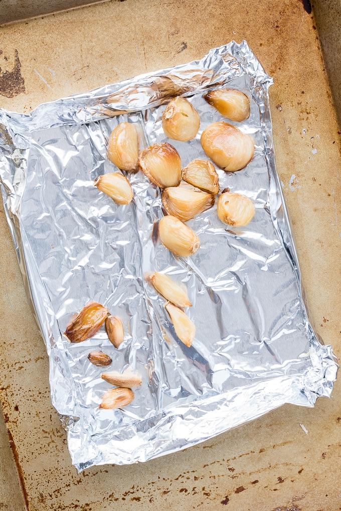 Roasted garlic cloves on a baking sheet