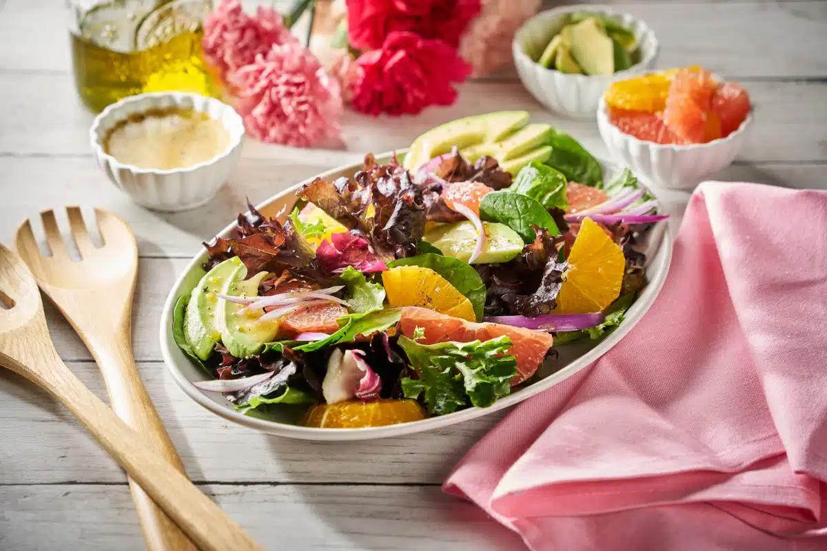 A bowl of spring citrus salad being prepared, showing the ingredients separately before mixing